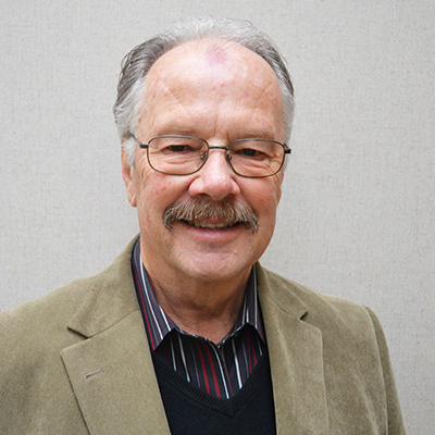 An older man with glasses smiling at the camera.