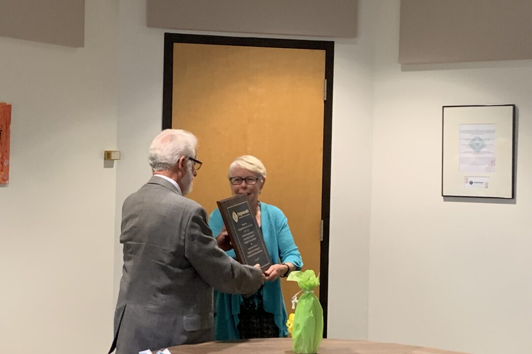 An award presentation ceremony where a man is handing a plaque to a smiling woman.