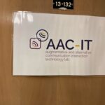 Sign for the aac-it lab, which stands for augmentative and alternative communication interaction technology lab, attached to a door.