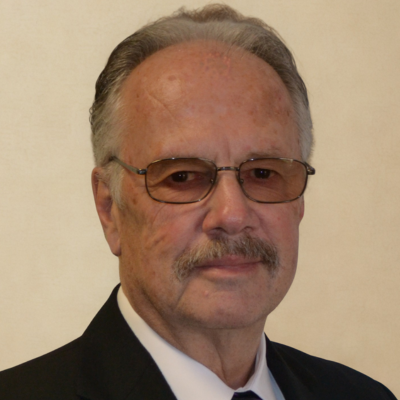 An older man with glasses smiling at the camera.